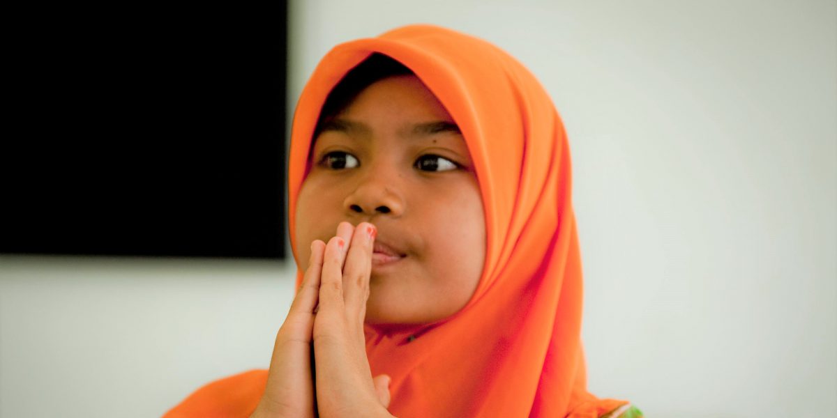 Young girl prayer with hands in front of her face.