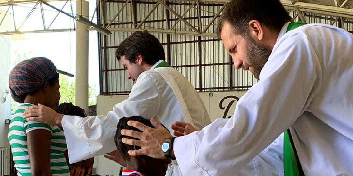 Fr. Brian Strassburger, SJ, and Fr. Louie Hotop, SJ, give blessings to migrants during Mass at Casa del Migrante in Reynosa, Mexico